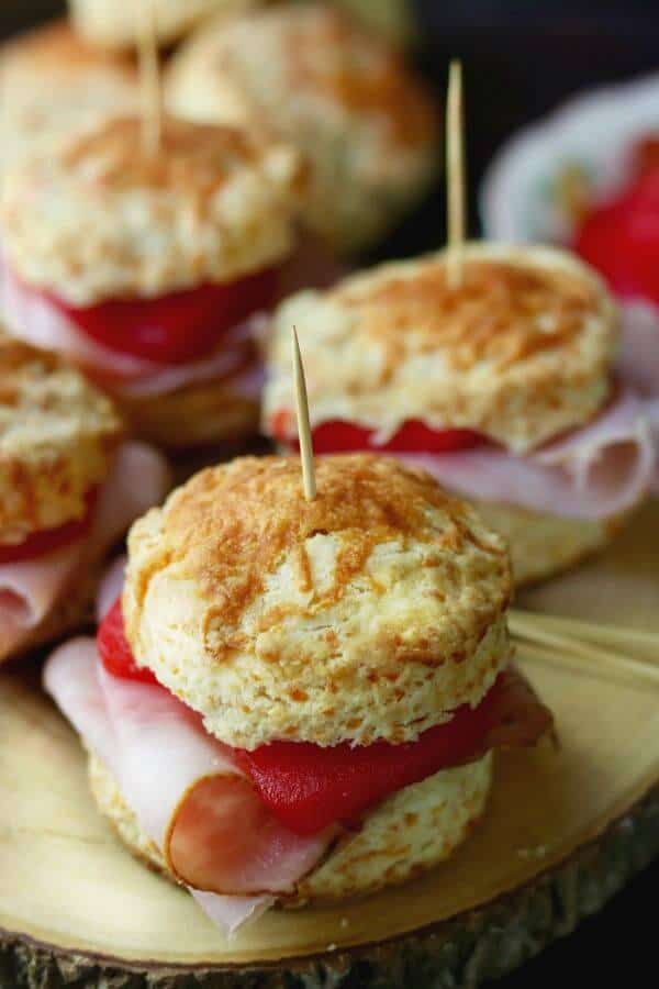 Cheddar cheese biscuits cut in half and filled with sliced ham and spiced apple rings to make ham sliders.