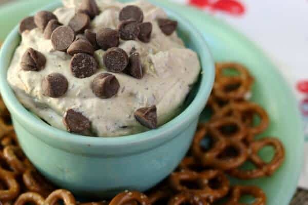 peanut butter chocolate chip cheesecake dip in a jadite bowl surrounded with crunchy pretzels