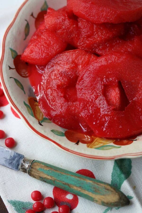 closeup of bright red spiced apple rings in a bowl.