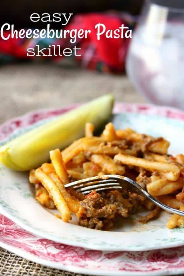 A serving of cheeseburger pasta skillet recipe on a light plate garnished with a dill pickle spear. Title image