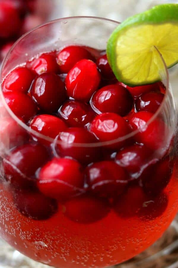 closeup of a bright red cranberry moscow mule cocktail with cranberries floating on the top