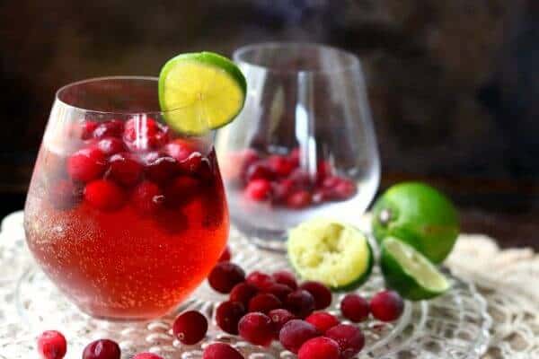 Cranberry Moscow Mule in a glass - an empty glass is in the background. Cranberries are at the base of the glasses.