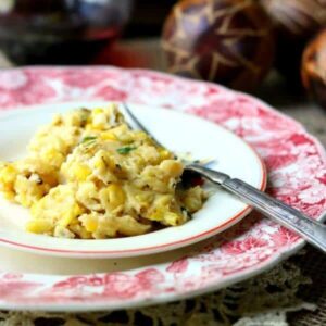 Southern corn pudding on a white plate with a red transferware plate underneath - square image for the recipe card