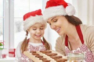 womanandchildwearingredsantaclaushatslookingatatrayofcookies featureimagebestgiftsforthegourmet