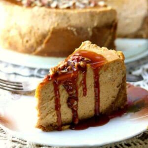 recipe image - a slice of pumpkin cheesecake with gingersnap crust is covered in homemade caramel sauce. A large cheesecake is in the background.