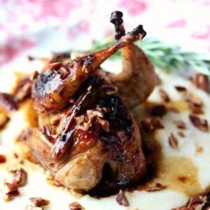 A whole, roasted quail on a bed of cheese grits.