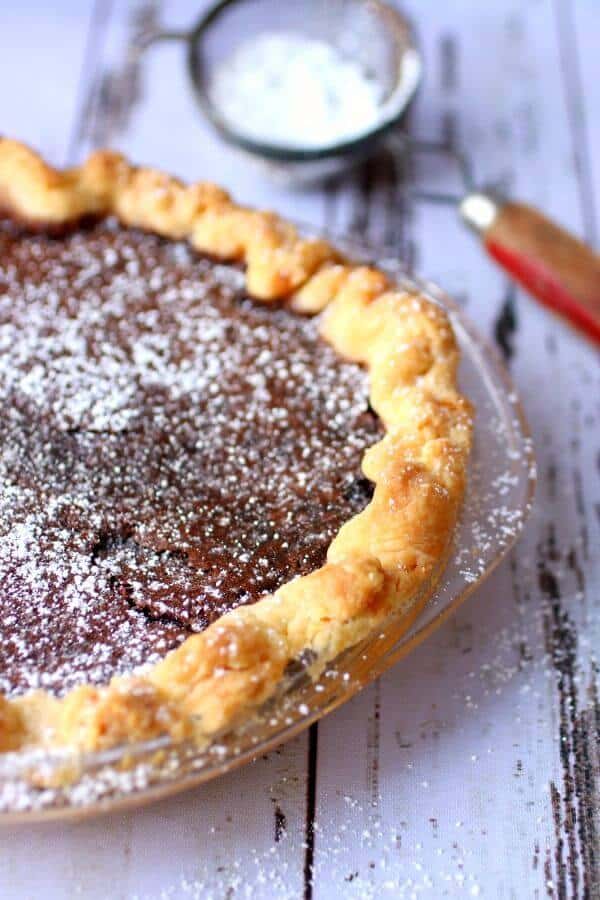 Close up of an uncut chocolate chess pie in a buttery crust.