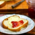 Slice of homemade bread with strawberry jam on it.