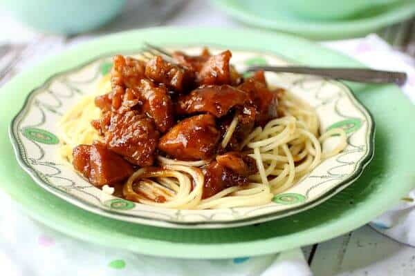 bourbon chicken with a bright, sticky glaze on a bed of pasta. Feature image