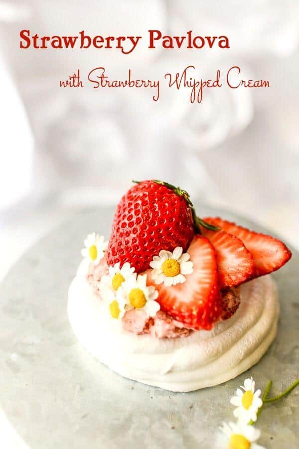 A small, white pavlova recipe with strawberry whipped cream and ripe strawberries on top. White background.