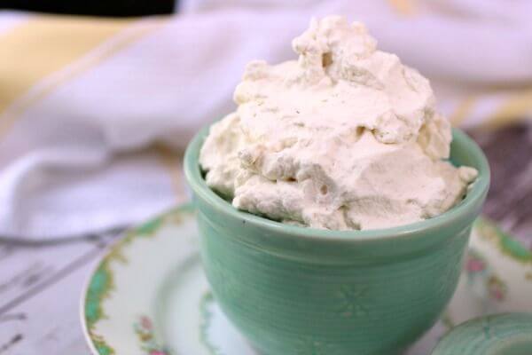 A container of homemade Cool Whip sits on a table.