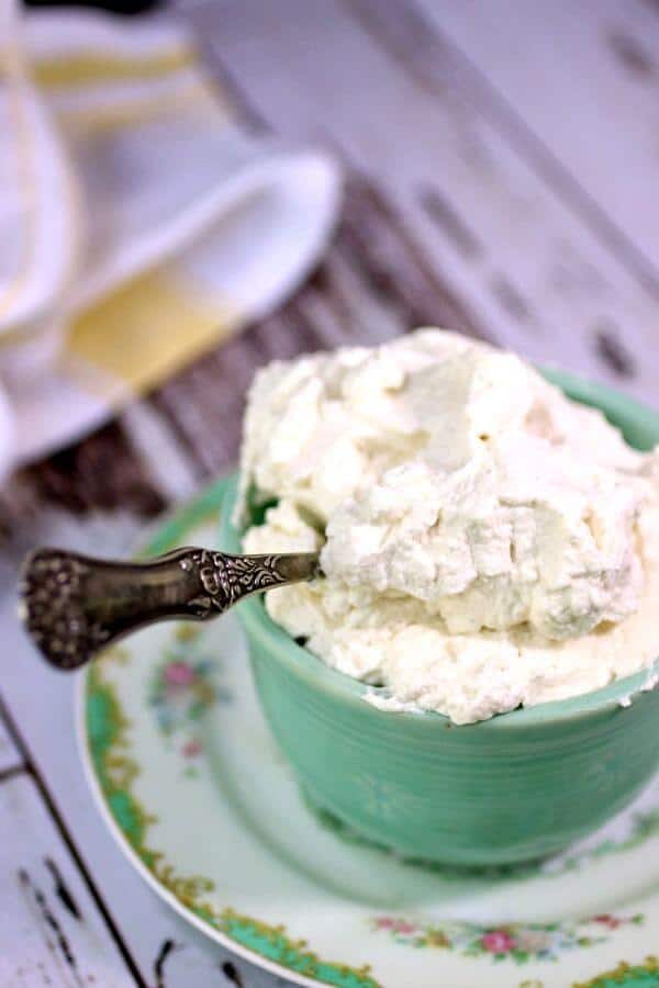 A green bowl of homemade Cool Whip is ready to serve with a silver spoon