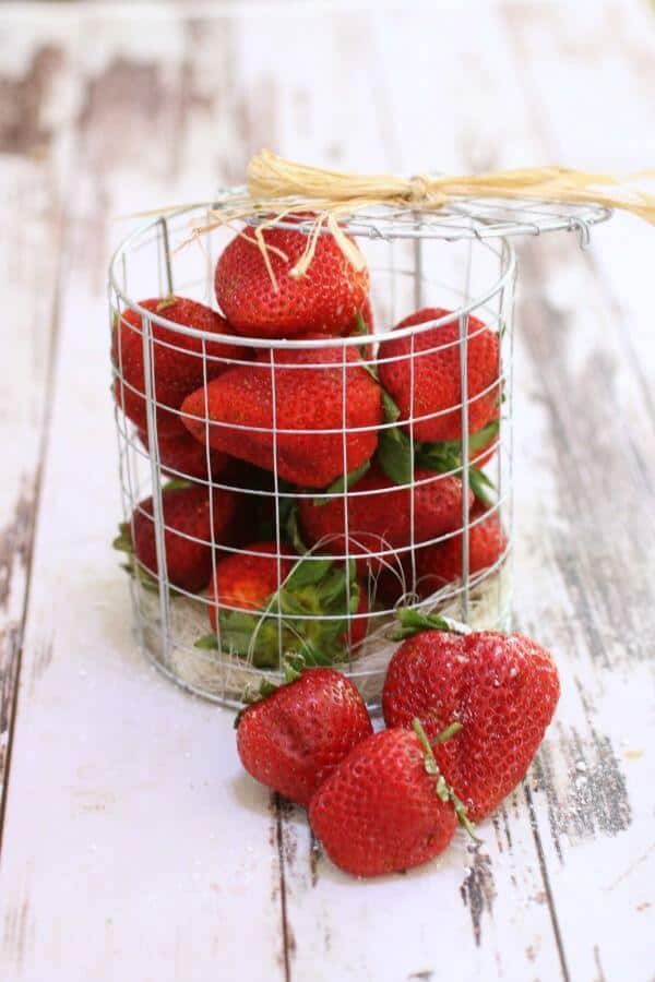 A container of fresh strawberries on a white table