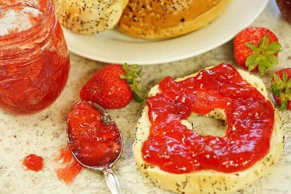 Strawberry jam has been spooned onto a bagel - optimized feature image.