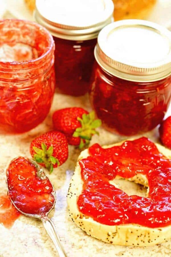 Strawberry jam is spread on a bagel