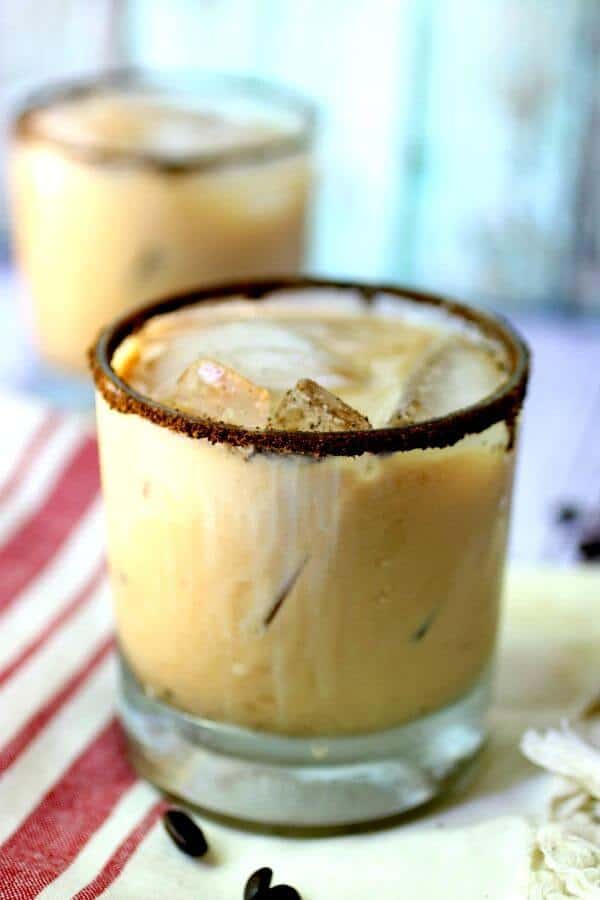 Two glasses of the iced coffee cocktail are placed on a red and white tea towel