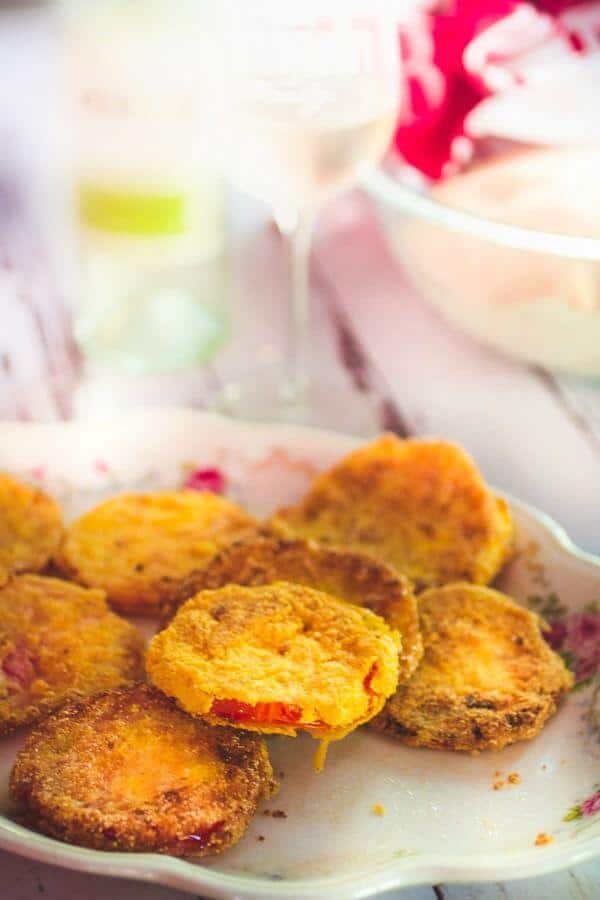 Crispy fried green tomatoes piled on a plate on a picnic table.