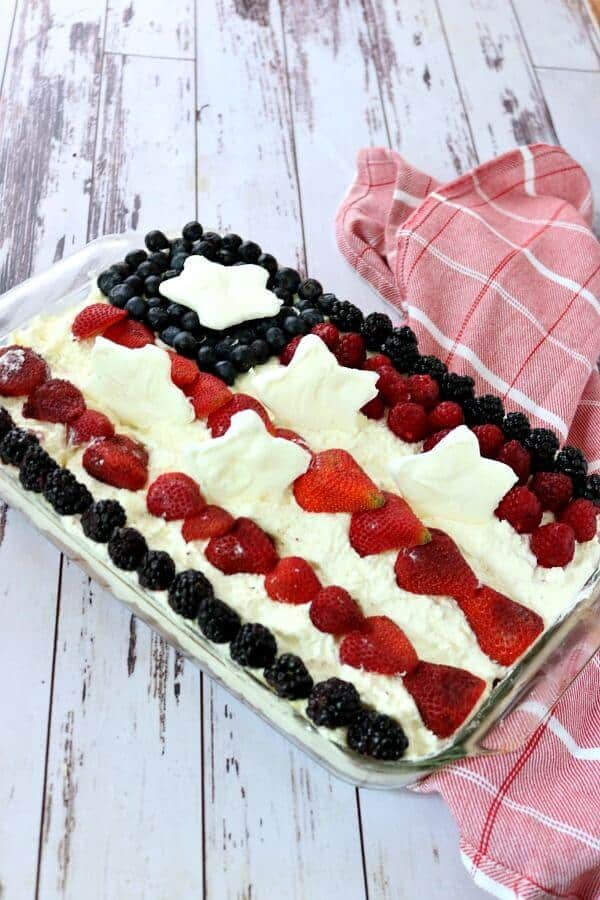 Square of Jello Poke cake with blueberries and raspberries on top.