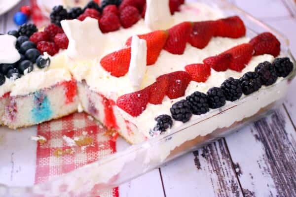 Red white and blue poke cake with a serving cut out showing the inside.