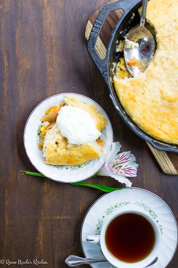 Easy peach cobbler recipe has a splash of bourbon. You'll love this classic southern dessert! #restlesschipotle #dessert #recipe #bourbon #peaches #southern #cobbler #oldfashioned Flat lay image of peach cobbler in a dish.