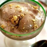 Closeup of brownie ice cream in a dish. Ice cream is melting and there are graham cracker crumbs sprinkled on to. Feature image.
