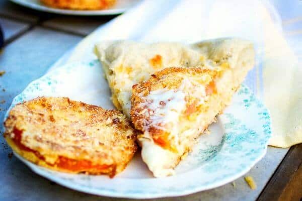 A slice of fried green tomato pizza next to a fried green tomato on a plate. Feature image.