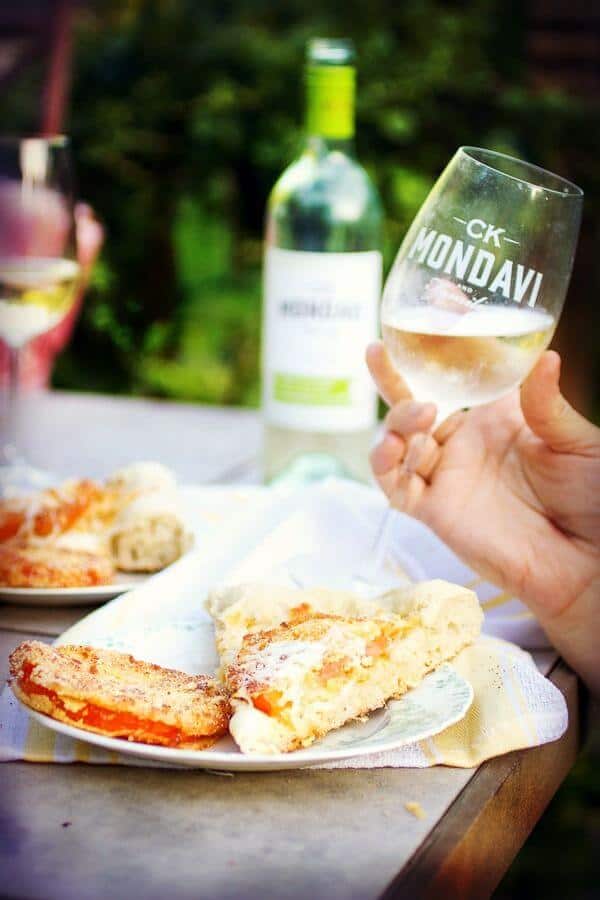 slices of fried green tomato pizza on a plate with a glass of white wine being raised.