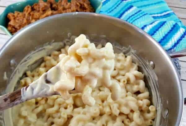 Spoon stirring cheese sauce into macaroni