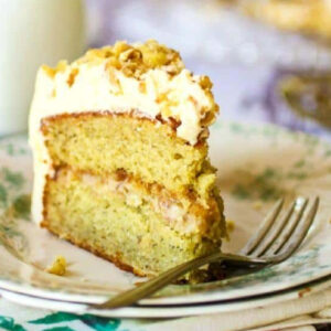 A slice of banana layer cake with gooey walnut filling and a thick creamy frosting.