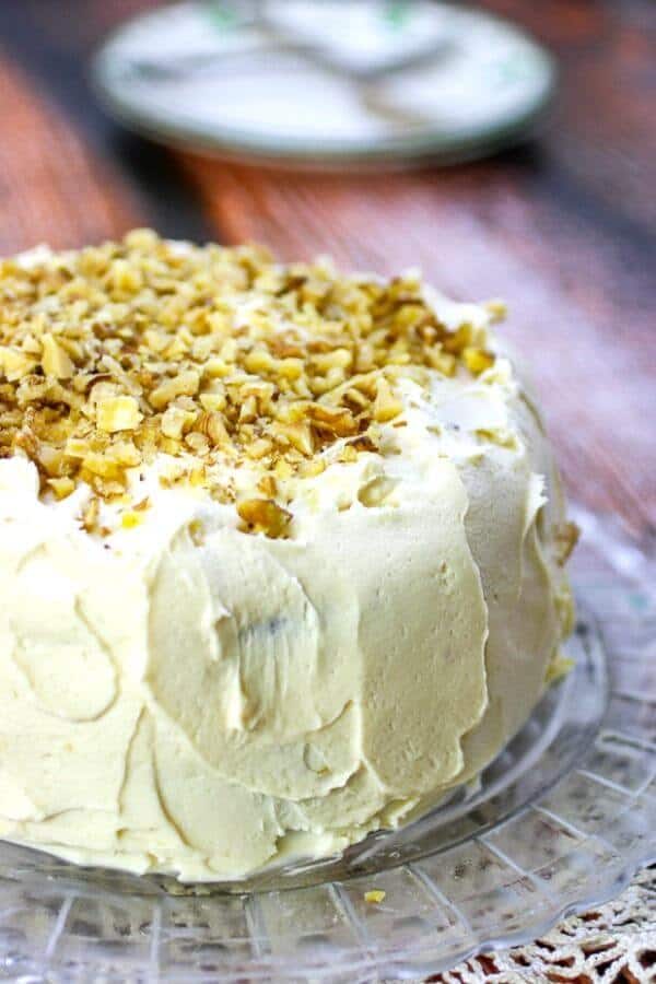 Two layer banana cake with cream cheese frosting on a cake plate