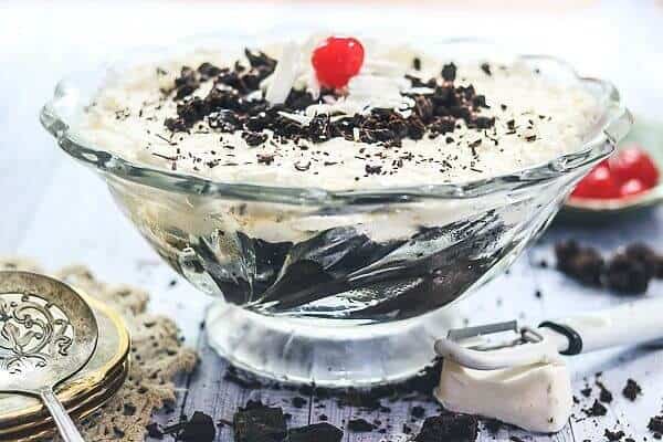 A glass punch bowl with layers of brownie trifle in it.