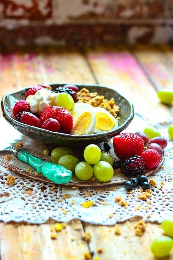 Fruit and granola in a pottery bowl on a wood table