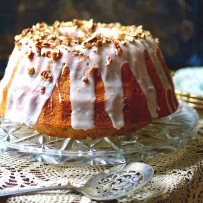 a bourbon cake with white glaze on a clear cake plate