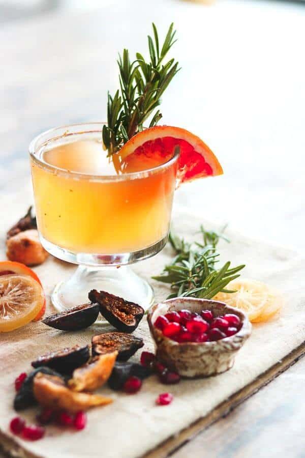 Old fashioned cocktail with an orange garnish and cut figs at the base of the glass.