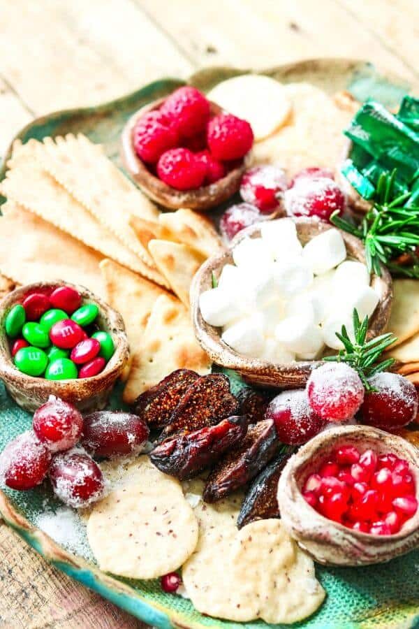 Figs, raspberries, grapes, and candy on a Christmas dessert tray.