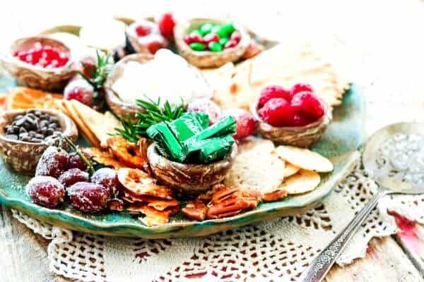 Green platter with candy and dried fruit on a lace doily.