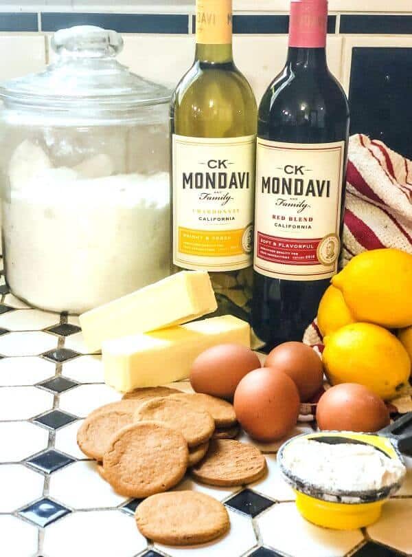 Lemons, cookies, and other ingredients for lemon bars on a tile countertop.