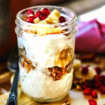 Layers of banana, nuts, cookies, and yogurt in a jar.