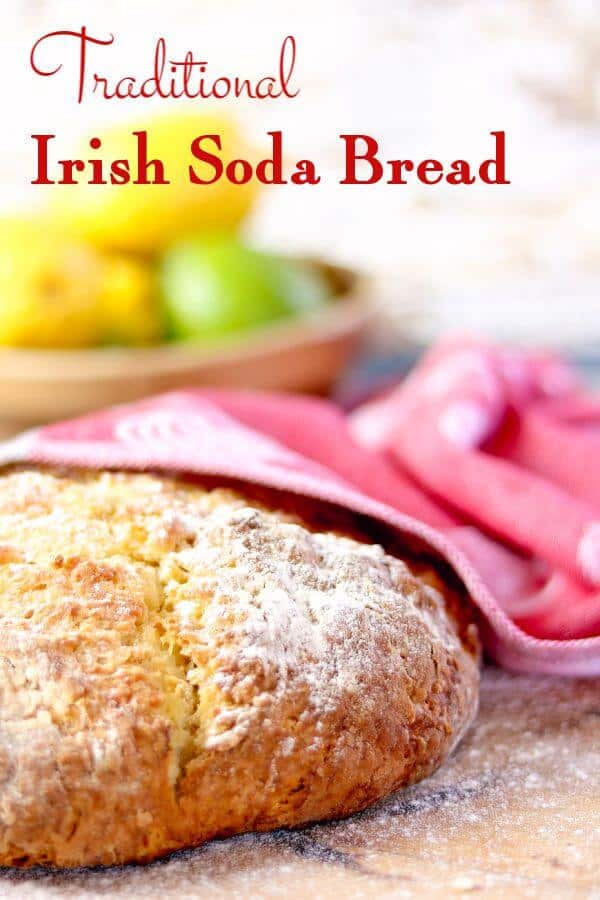 Round loaf of Irish soda bread cools under a red tea towel