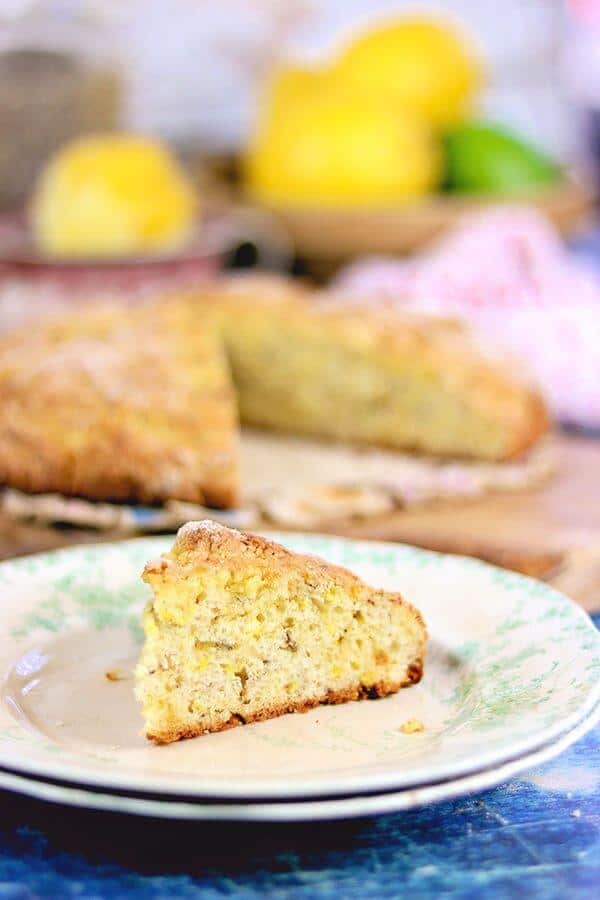 A freshly cut wedge of lavender lemon Irish soda bread waits on a vintage plate.