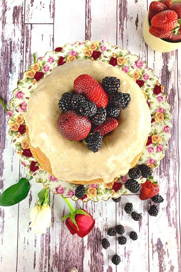 Looking down on a pound cake with strawberries and blackberries in the center.