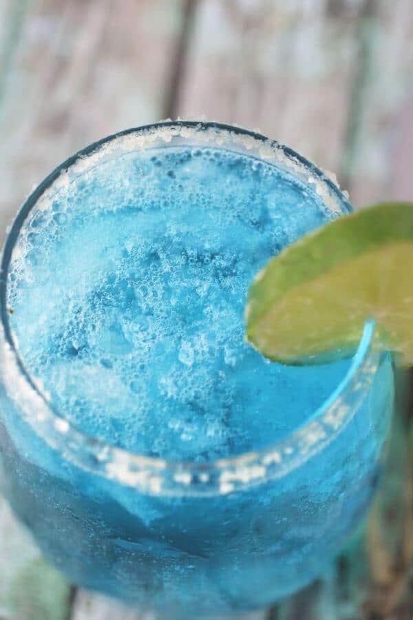 Top view of a glass of blue cocktail with ice.