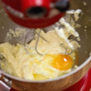 A raw egg being mixed into batter.