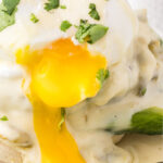 A closeup of southwestern eggs benedict with the yolk flowing over the side. Title text overlay for Pinterest.
