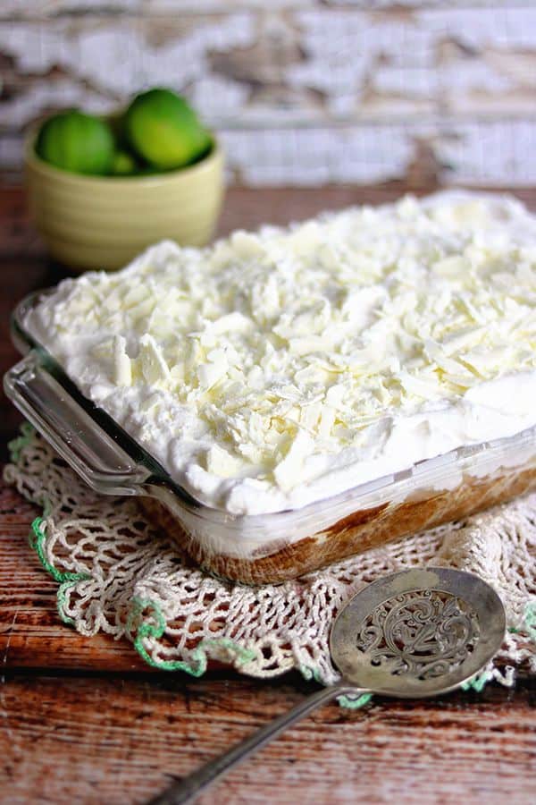 A cake covered in whipped cream and white chocolate on a wooden table.