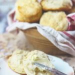 Buttermilk biscuits being spread with butter.