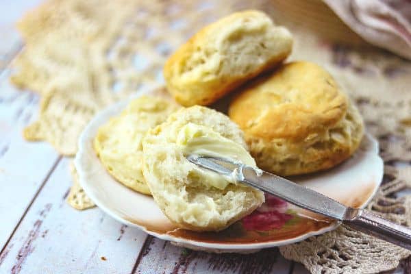 Horizontal image of a plate of biscuits on a lace table cloth.