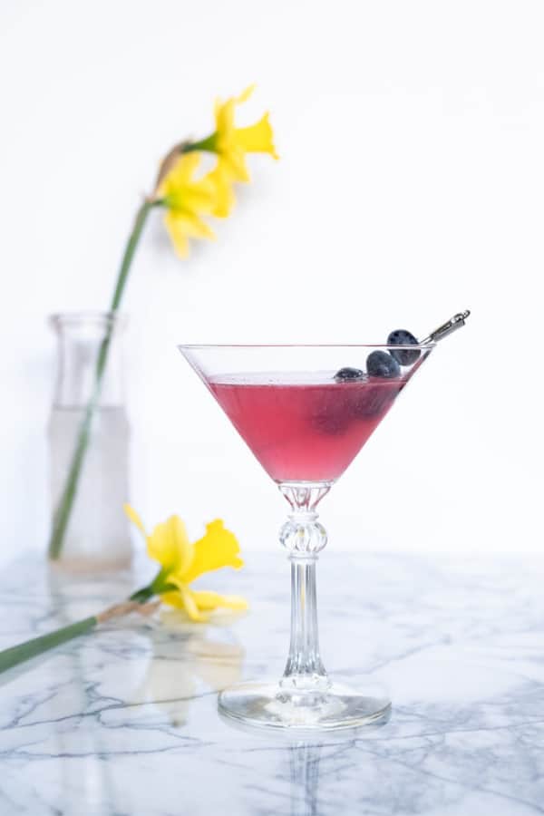 Blueberry martini in a glass garnished with blueberries.