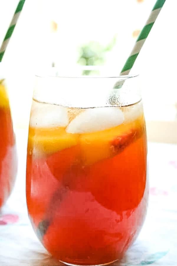 Bourbon peach tea in two glasses with green straws.