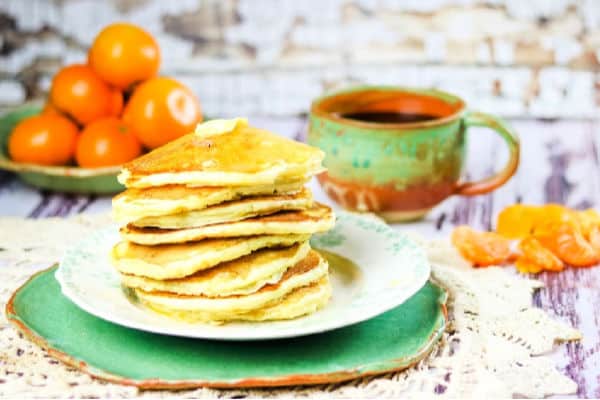stack of buttermilk pancakes with oranges in the background.